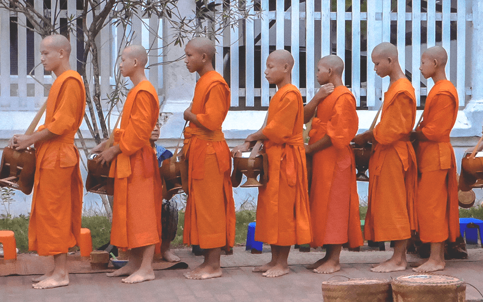 Morning alms ceremony where monks line up to receive their daily ration of food from locals