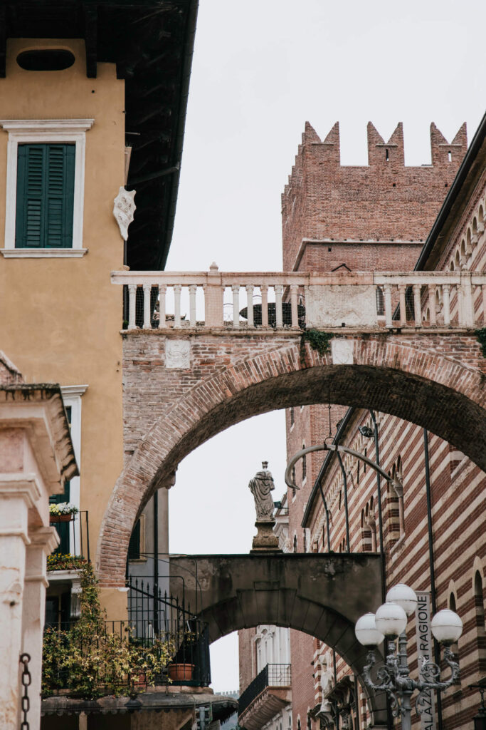 Arches on Piazza delle Erbe having a whale bone hanging from it and giving way to Terre Dei Lamberti