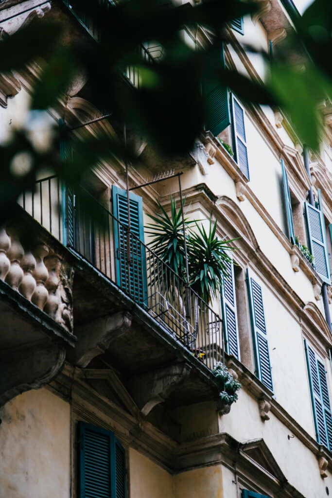 Tropical white facade with blue shutters and palmtrees in Verona old Town