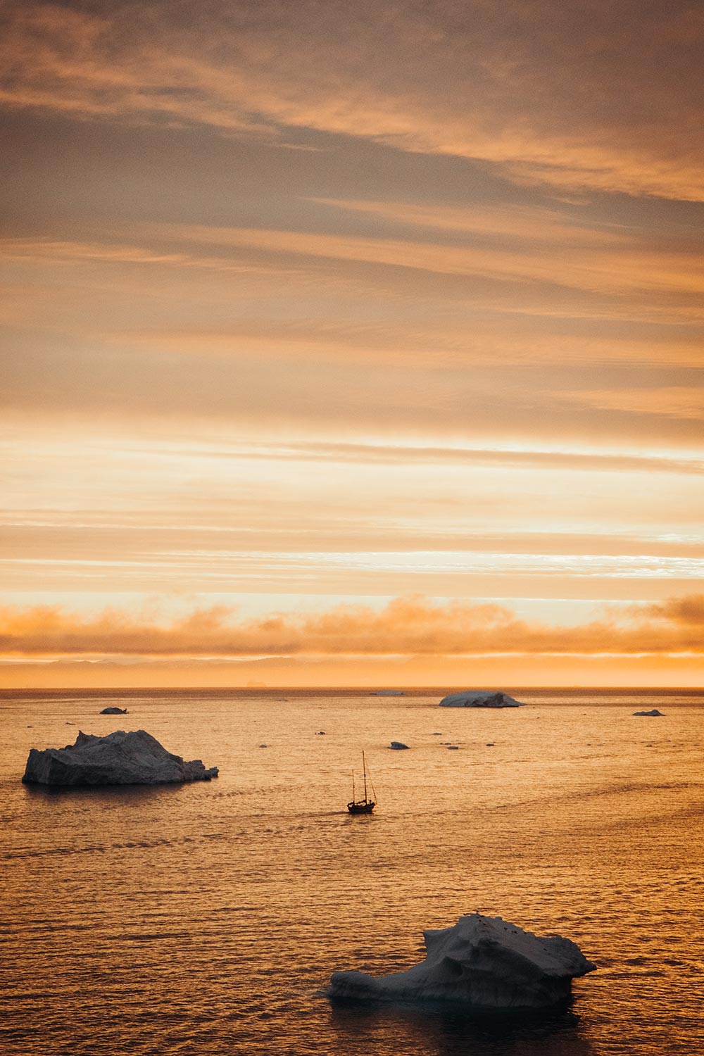 Sunset reflections on the icy waters during a Greenland iceberg tour